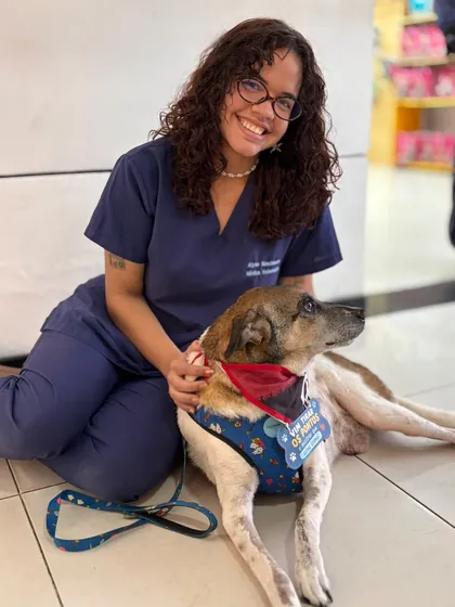 Veterinária da Clínica Bixo's sentada acariciando um cão resgatado