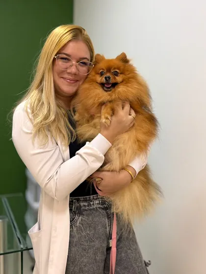Veterinária da Clínica Bixo's de óculos segurando um lulu da pomerânia
